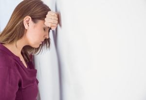 Depressed woman leaning her head against a wall