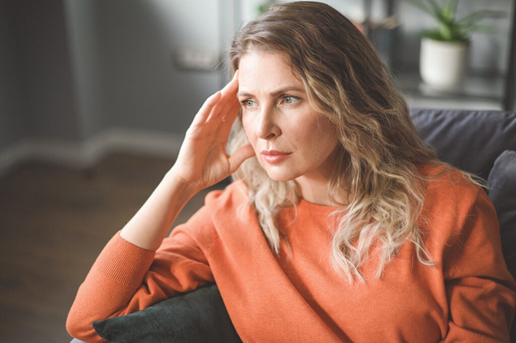 Woman sitting thoughtfully while learning about depression support and recovery.
